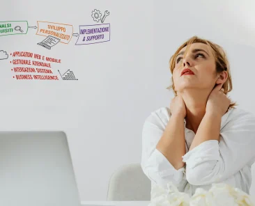 Una impiegata davanti ad un computer si preoccupa portando le mani al collo in segno di stanchezza.